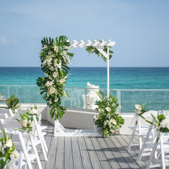 Beach wedding ceremony flowers with tropical greenery and white blooms created by Victoria Florist in Barbados.