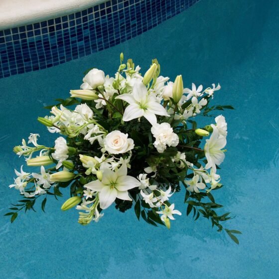 Floating white floral arrangement with lilies and greenery created by Victoria Florist for a Barbados event.