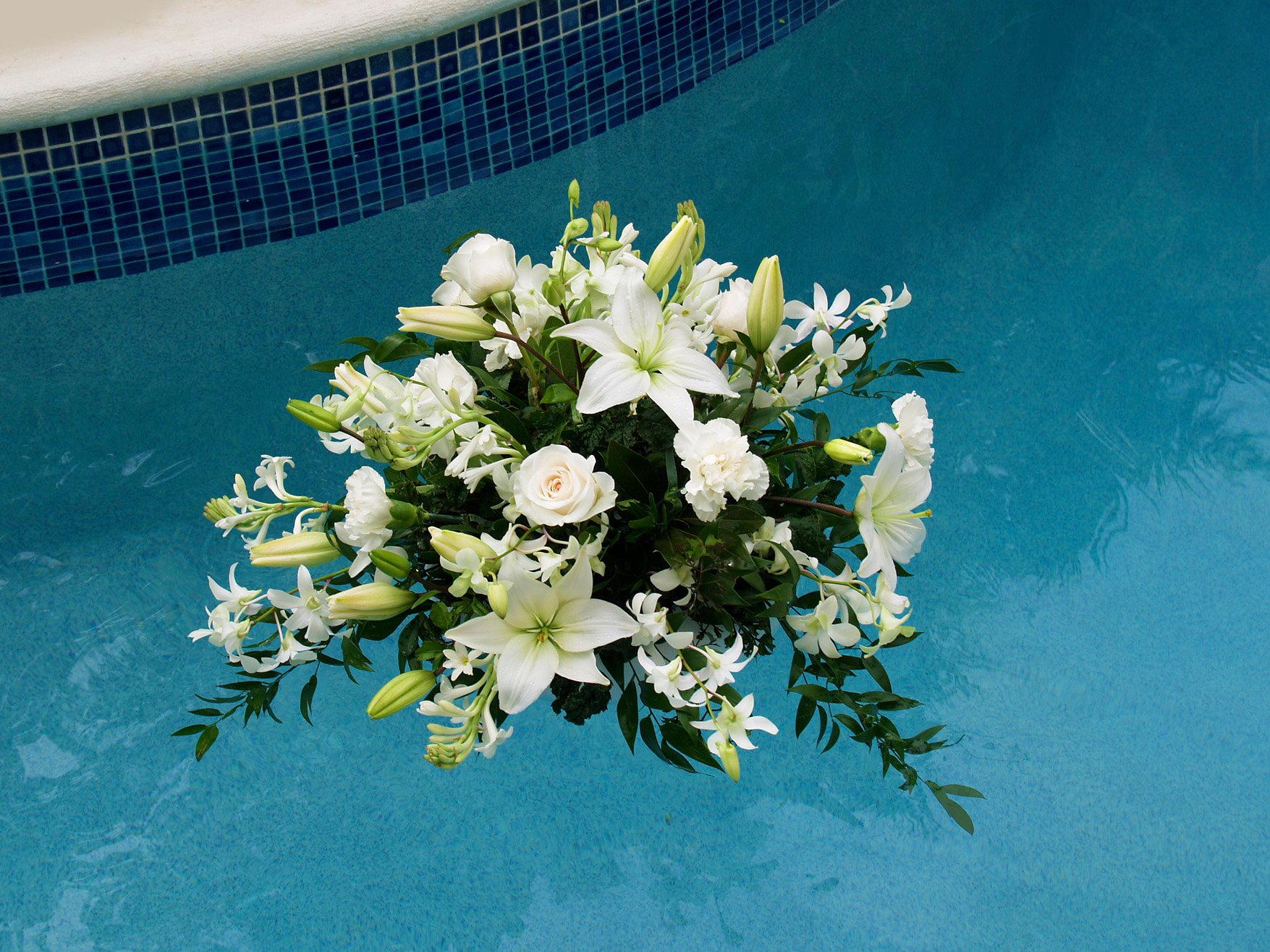 Floating white floral arrangement with lilies and greenery created by Victoria Florist for a Barbados event.