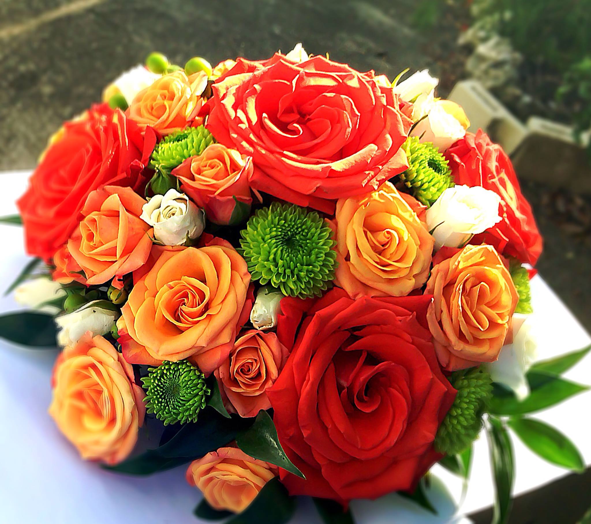 Bright floral arrangement with orange and red roses created by Victoria Florist in Barbados.
